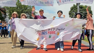 横断幕を手にリレーウオークの先頭を歩くがんの当事者や経験者ら＝みなとのもり公園