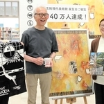 展覧会入場者４０万人目となり、記念品とともに記念撮影する清水明さん（中央）、由美さん（右）夫妻＝横尾忠則現代美術館