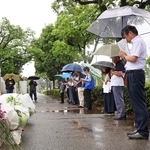 雨が降り続ける中、神戸高塚高校の校門前で黙とうする人たち＝神戸市西区美賀多台９