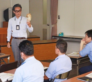 ツキノワグマの頭蓋骨を署員に示す岡居宏顕さん＝有馬署