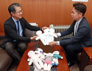 神戸キワニスクラブの秀平徹晃会長（右）からキワニスドールを受け取る黒田良祐病院長＝神戸大医学部付属病院