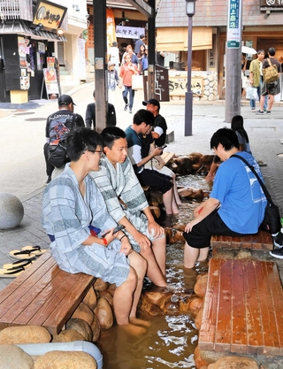 ぬるめの温度に設定された足湯で疲れを癒やす観光客ら＝神戸市北区有馬町