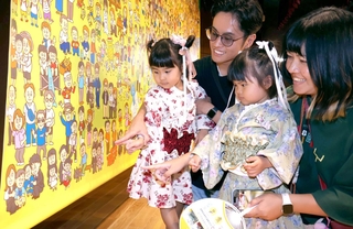応募した写真が使われたイラストを見つけ、喜ぶ家族＝兵庫区役所