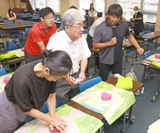 胸骨圧迫の方法を伝えるライフセーバーの飯沼誠司さん（右）＝神戸市中央区東川崎町１、神戸市総合教育センター