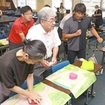 胸骨圧迫の方法を伝えるライフセーバーの飯沼誠司さん（右）＝神戸市中央区東川崎町１、神戸市総合教育センター
