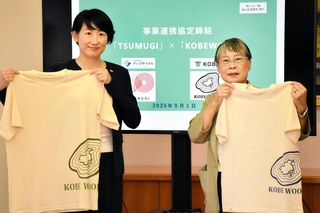 広葉樹の枝葉から製造予定のＴシャツを持つ神戸市の黒田慶子副市長（右）と一般社団法人アップサイクルの嘉納未来理事＝神戸市役所