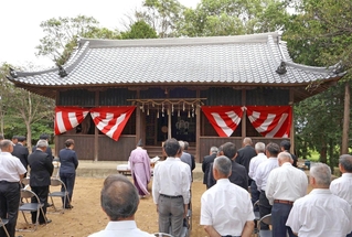 屋根瓦をふき替えた拝殿の前で竣工式を執り行う地元住民ら＝西区岩岡町岩岡