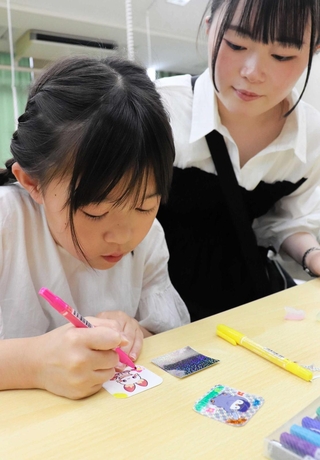 アドバイスを受けながらキラキラ光るシール作りに熱中する参加者＝神戸市立工業高等専門学校
