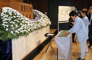 原爆で亡くなった人を悼み、花を手向ける参列者＝中央区東町、中央区文化センター