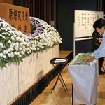 原爆で亡くなった人を悼み、花を手向ける参列者＝中央区東町、中央区文化センター