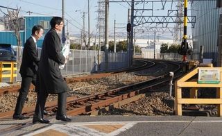 ２月２５日、花束を手に尼崎ＪＲ脱線事故の現場に向かうＪＲ西日本の長谷川一明社長（右）。奥は事故があった福知山線のカーブ＝尼崎市