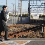 ２月２５日、花束を手に尼崎ＪＲ脱線事故の現場に向かうＪＲ西日本の長谷川一明社長（右）。奥は事故があった福知山線のカーブ＝尼崎市