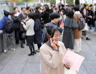 司法試験に合格したことを電話で知らせる女性（手前）＝12日午後、東京・霞が関