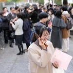 司法試験に合格したことを電話で知らせる女性（手前）＝12日午後、東京・霞が関
