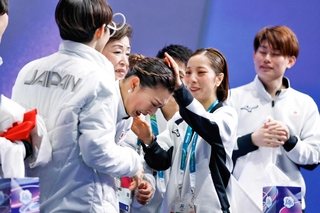 団体女子フリーの得点を確認し、感極まった坂本花織をなでる三浦璃来（右から２人目）＝８日、イタリア・ミラノ（共同）