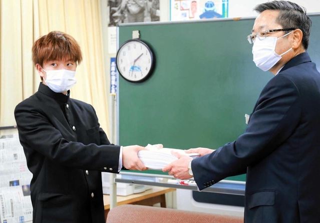兵庫県教育委員会の西田健次郎教育次長（右）に約１万６千人分の署名を手渡す男子高校生＝兵庫県庁