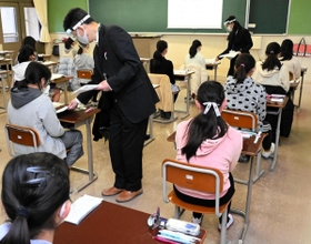 机の間隔を空け、マスクとフェースシールド姿の試験官が問題を配る試験会場＝１６日午前、神戸市灘区土山町、親和中学校（撮影・後藤亮平）