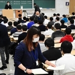 マスク姿で受験生に試験用紙を配る試験官＝１６日午前、神戸市東灘区岡本８、甲南大岡本キャンパス（撮影・中西幸大）