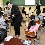 机の間隔を空け、マスクとフェースシールド姿の試験官が問題を配る試験会場＝１６日午前、神戸市灘区土山町、親和中学校（撮影・後藤亮平）