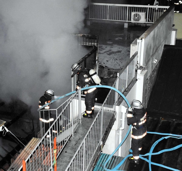 煙が上がる民家で消火を試みる消防隊員ら＝２７日未明、三木市本町