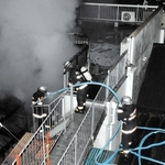 煙が上がる民家で消火を試みる消防隊員ら＝２７日未明、三木市本町