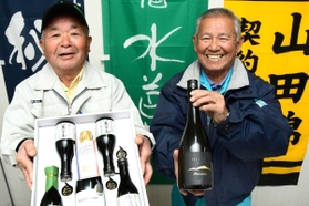 三木・別所産の山田錦を使った日本酒を手に喜ぶ正井清さん（左）と大西正行さん＝三木市別所町花尻１、ＪＡみのり三木営農経済センター