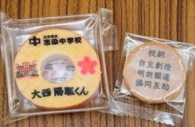 生徒の名前をあしらったバウムクーヘンと校訓を刻んだクッキー＝志染中学校