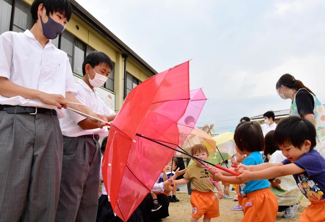 三木高生が園児に贈った「スカイアンブレラ」。色鮮やかな傘におおはしゃぎしていた＝三木市加佐