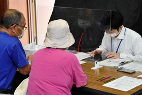 希望を聞き取りながらタブレット端末で手続きを代行する公民館職員（右）＝自由が丘公民館
