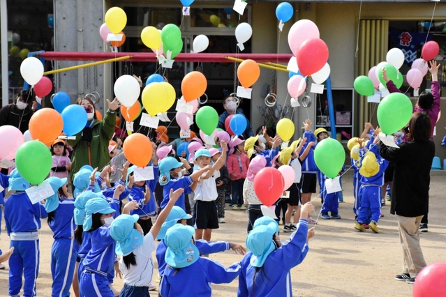飛ばした風船を見上げる子どもたち＝三木市加佐