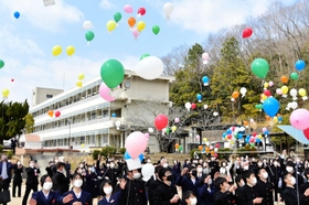 校舎を背に一斉に空に舞い上がる風船＝星陽中学校