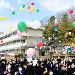 校舎を背に一斉に空に舞い上がる風船＝星陽中学校