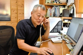 電話で寄せられた相談に対応する岩崎吉男さん＝三木市久留美