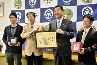 賞状を手に入賞を喜ぶ「稔樹」の田中誠代表（左から２人目）と仲田一彦市長（同３人目）ら＝三木市役所