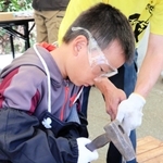 赤く熱したくぎをペーパーナイフへ加工する子ども＝かじやの里メッセみき