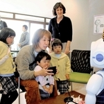 対話ロボットとクイズを楽しむ親子と開発者の１人、インディアナ大のシャバノビッチ教授（右後ろ）＝三木市自由が丘東１、たかはしさんち