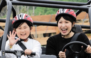 バギーに乗って満面の笑顔を浮かべる親子＝三木市細川町、ネスタリゾート神戸