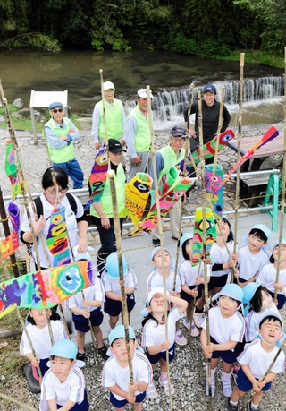遊歩道を飾るミニこいのぼりを手にする園児たち＝三木市吉川町