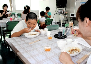 普段は社員食堂の部屋でカレーライスを頰張る子どもら＝三木市大村、前田精版印刷所
