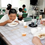 普段は社員食堂の部屋でカレーライスを頰張る子どもら＝三木市大村、前田精版印刷所