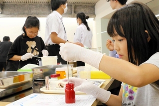 複数の材料を調合して、口紅作りに挑戦する子どもたち＝三木市緑が丘町本町２、ナリス化粧品兵庫工場