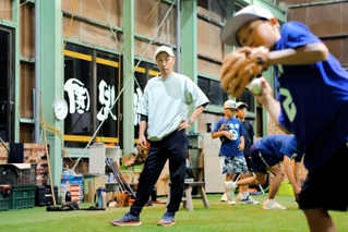 室内練習場で守備練習に取り組む子どもたちを見守る興梠正典さん＝三木市福井３