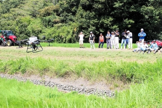 ドローンを使った肥料散布を見学する参加者ら＝三木市吉川町上中