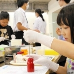 複数の材料を調合して、口紅作りに挑戦する子どもたち＝三木市緑が丘町本町２、ナリス化粧品兵庫工場