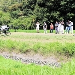 ドローンを使った肥料散布を見学する参加者ら＝三木市吉川町上中