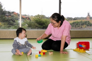 雄大な景色を見渡せるホテルのスペースで、預かった子どもと遊ぶ寺尾直美さん＝ネスタリゾート神戸