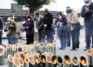 鎮魂の竹灯籠の前で黙とうする参列者＝１７日午後２時４６分、三木市末広１