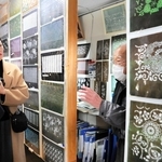 筒井俊雄さん（右）から三木の染め型紙の特徴を聞く喜多方市の木幡江里子さん（左端）とデザイナーの江畑芳さん＝三木市大塚２、ギャラリー湯の山みち