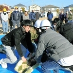 負傷者役の住民を毛布を使って運ぶ訓練に取り組む地域住民ら＝自由が丘中央公園