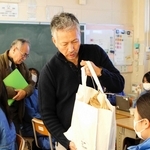 １億円の紙幣と同じ重さのバッグを生徒に渡し、体感させる学校運営協議会の委員ら＝自由が丘中学校